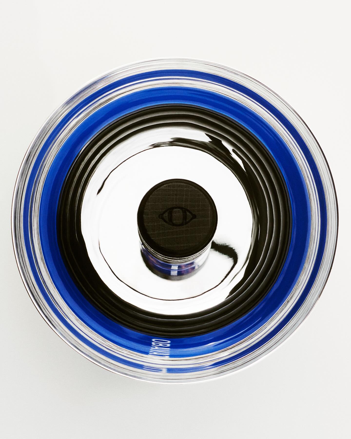 Eye-shaped logo on container of face cream in blue and black circular patterns in a studio shot from an overhead angle.