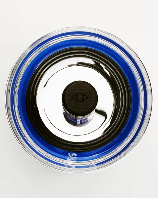 Eye-shaped logo on container of face cream in blue and black circular patterns in a studio shot from an overhead angle.