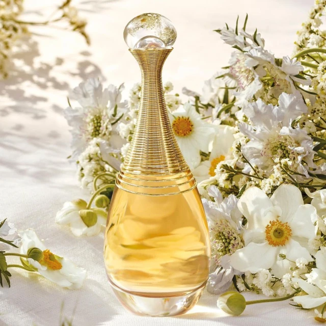 Elegant perfume bottle surrounded by white flowers on a white tablecloth, bathed in soft light, creating a luxurious, floral-themed ambiance.