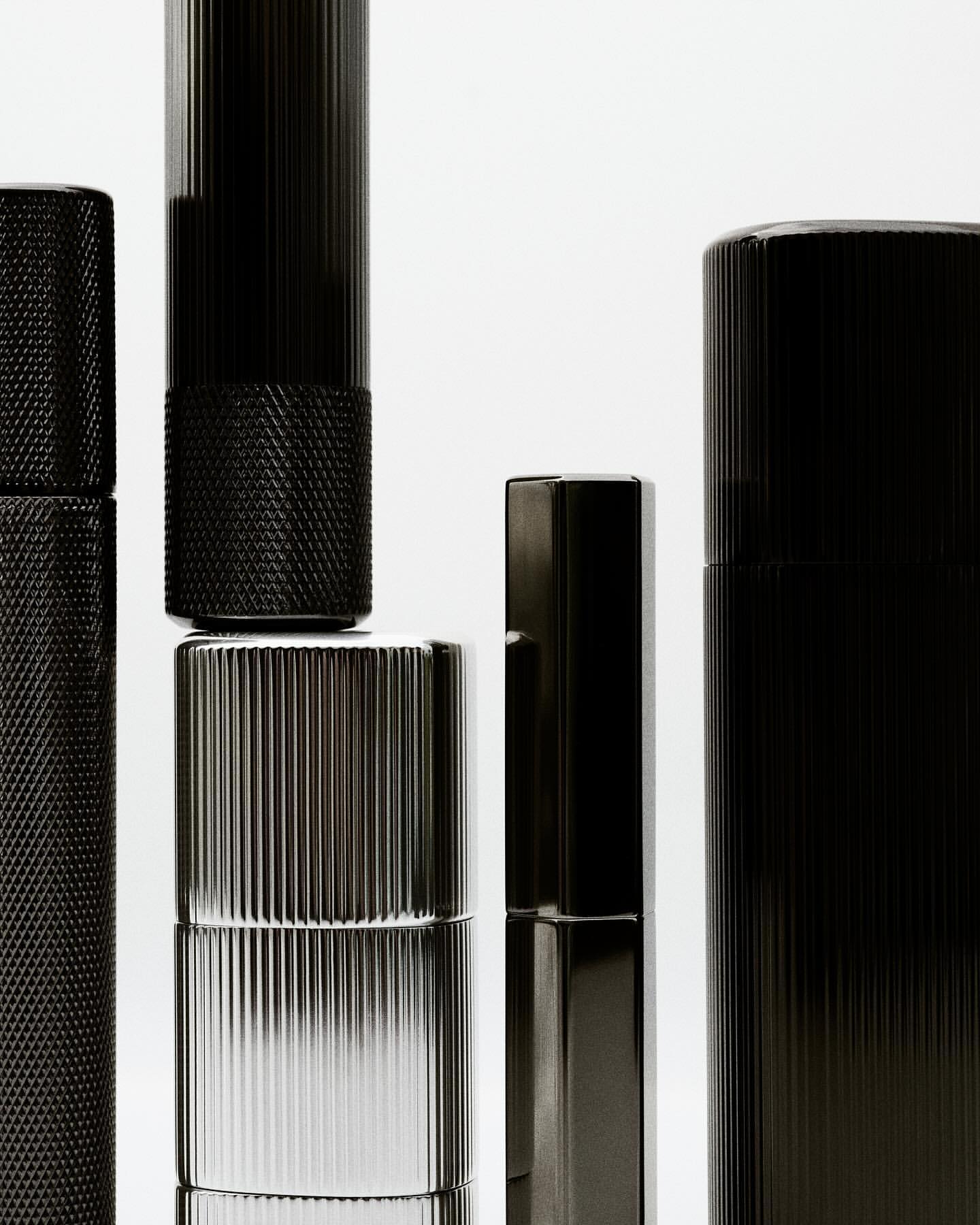 Still life of black and silver cylinders against a white background, showcasing their metallic textures and sleek, modern designs.