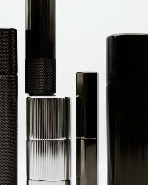 Still life of black and silver cylinders against a white background, showcasing their metallic textures and sleek, modern designs.