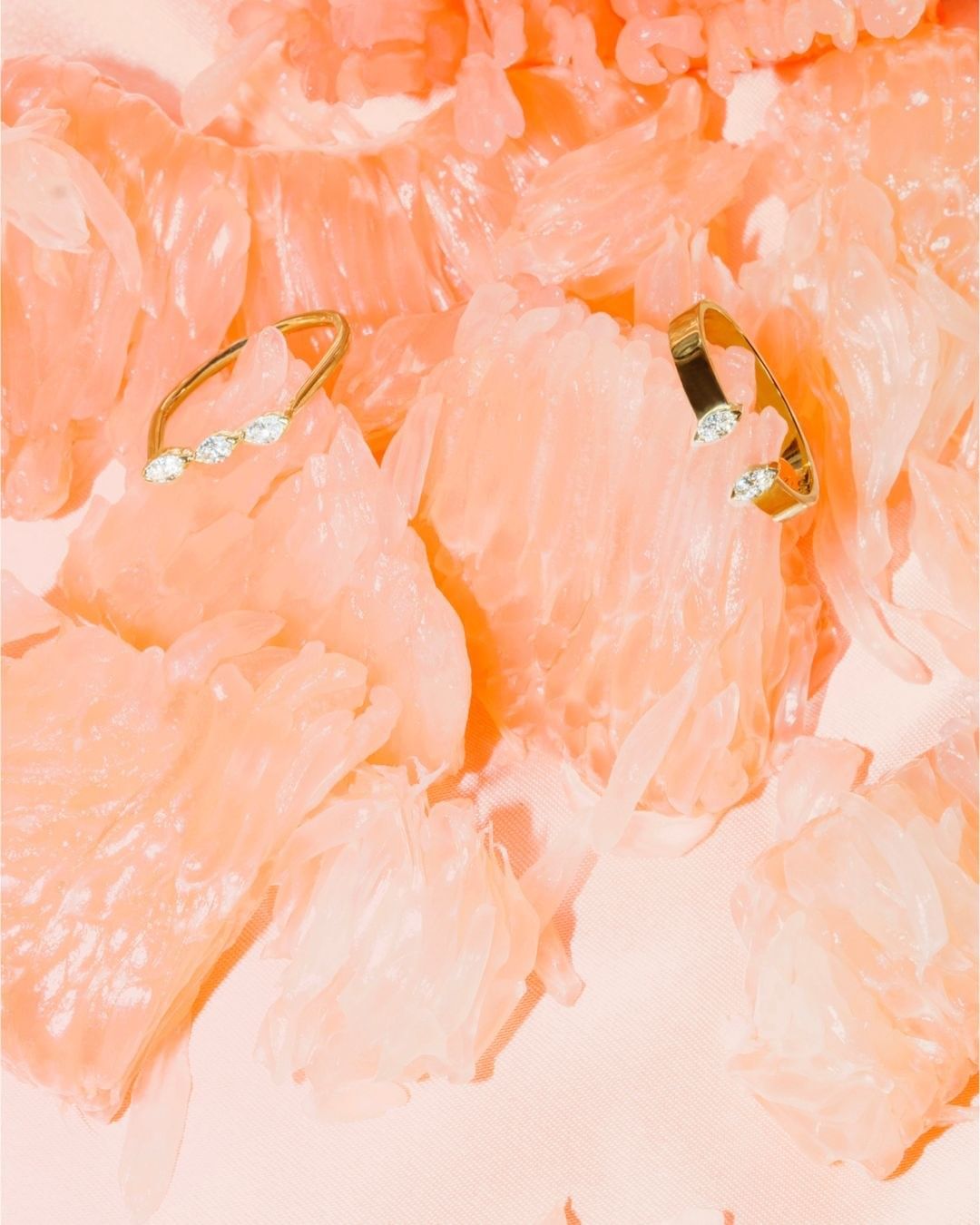 Two gold cuff earrings sit on textured grapefruit pieces in a bright and airy setting, showcasing jewelry and fresh fruit.