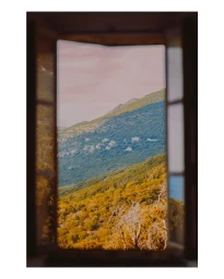 View of a green mountainous landscape through an open wooden window frame