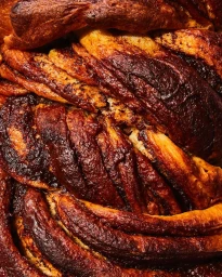 Close-up macro shot of braided chocolate babka pastry showing textured layers and dark crust baked details by Linda Xiao