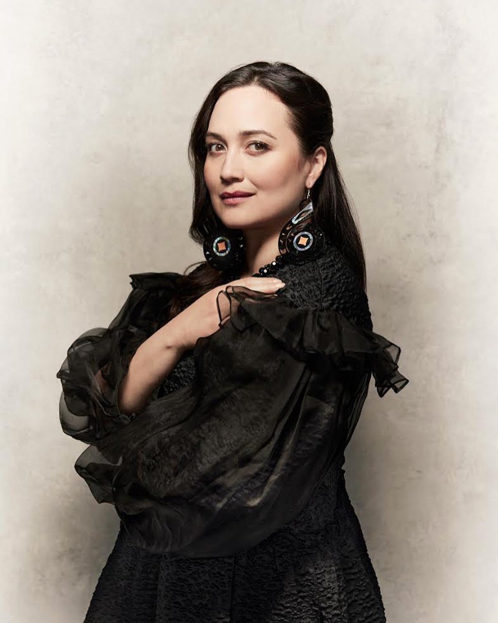 Elegant portrait of a woman with dark hair and a black dress, posing against a neutral backdrop, showcasing fashion and portrait photography.