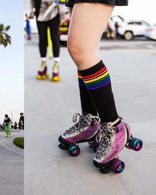 Person on roller skates wearing rainbow socks outdoors on a sunny day with palm trees and other skaters in the background.