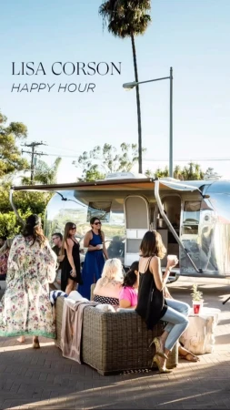 Outdoor social gathering in front of an Airstream trailer, featuring a group of people and a sunny, casual atmosphere.