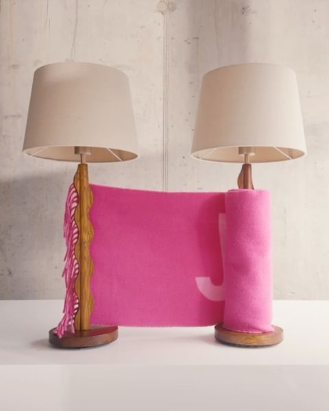Two lamps with pink fabric and wooden supports, set against a neutral background, showcasing interior decor elements and textures.