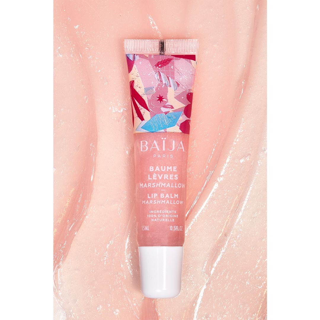 Close-up studio shot of Baija Paris lip balm, showcasing colorful floral design and smooth texture on a glossy pink surface.