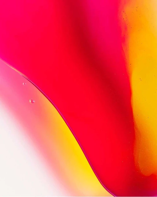 Abstract, macro photograph of vividly colored liquids blending, featuring flowing textures in shades of red, yellow, and white.
