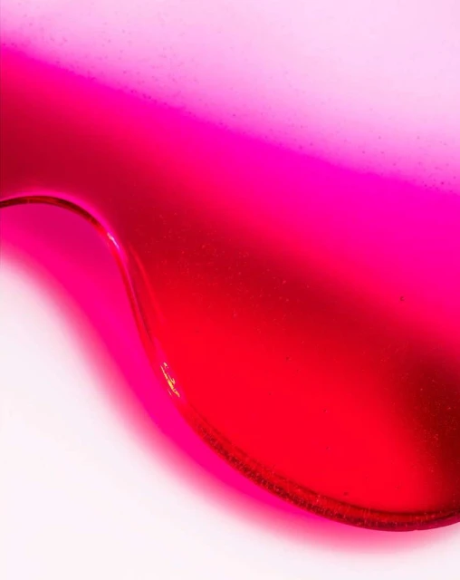 Abstract close-up of a curved surface with bright pink and red tones, creating a visually striking gradient effect.