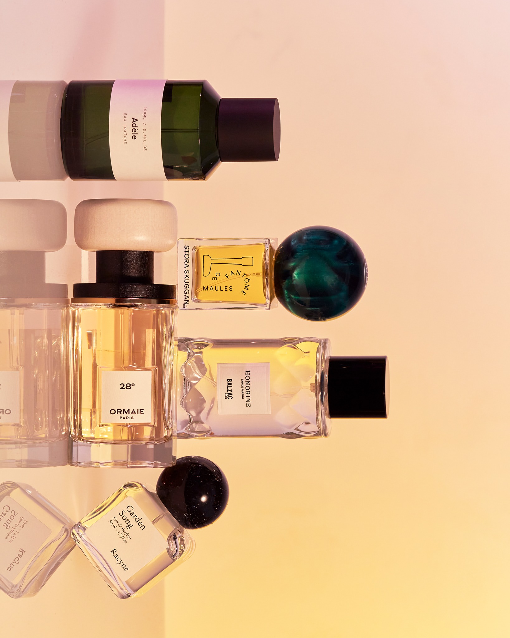 Several perfume bottles with white and black caps arranged against a warm gradient background