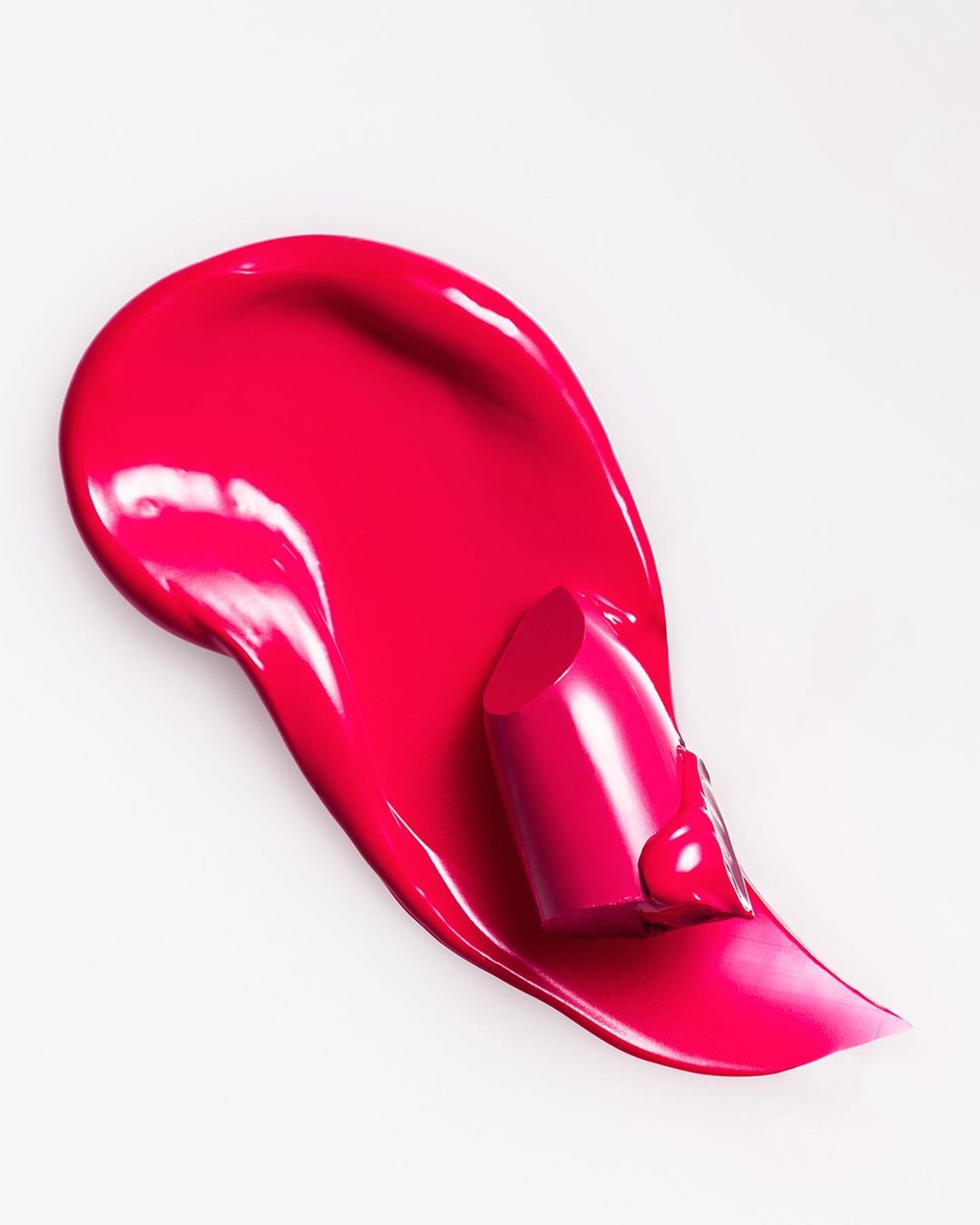 Vibrant pink lipstick and smear on white background, glossy makeup, beauty product shot for cosmetics or beauty industry.