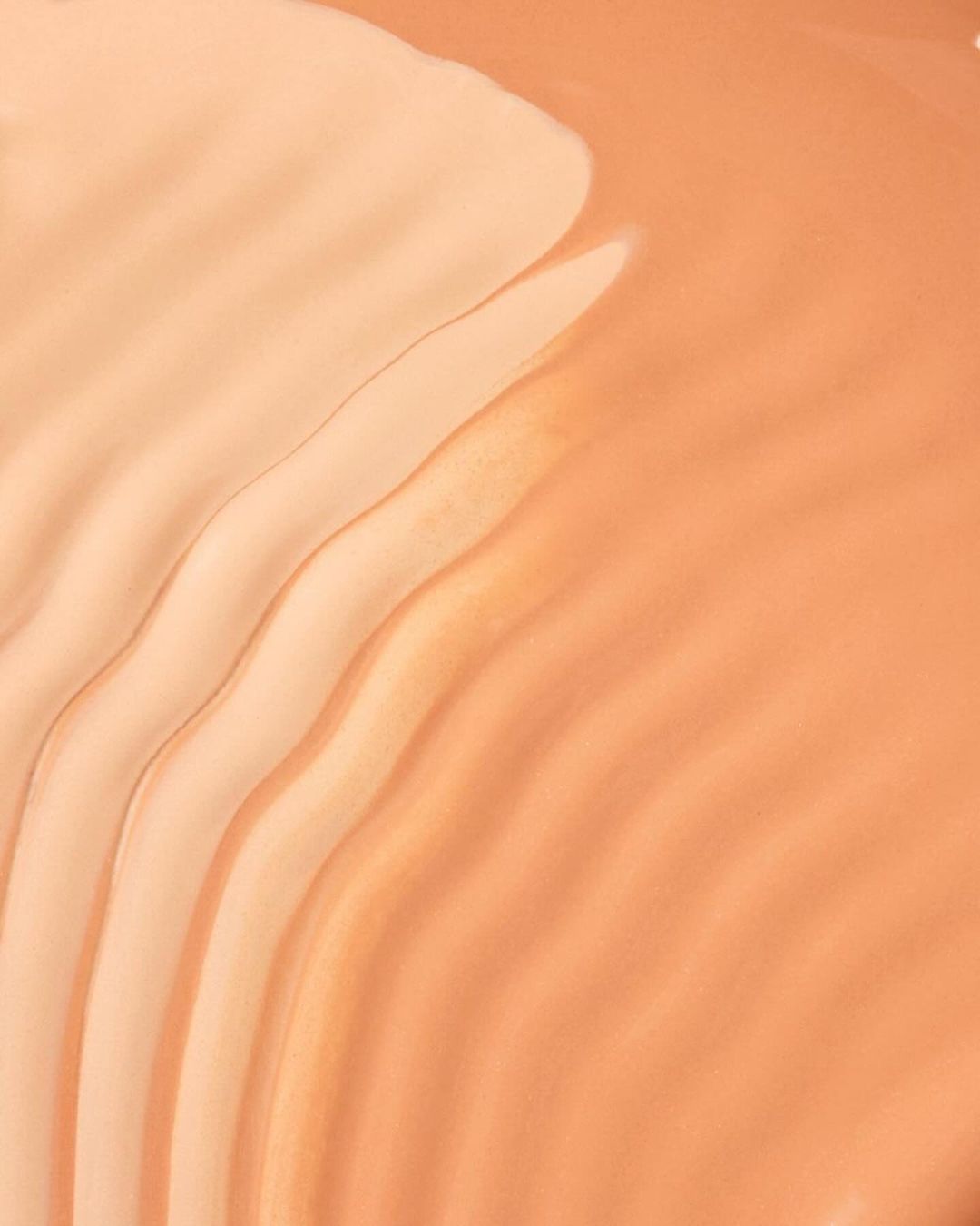 Beige and peach foundation swatches creating a wavy gradient. Abstract beauty shot for cosmetics, makeup, or skincare product.