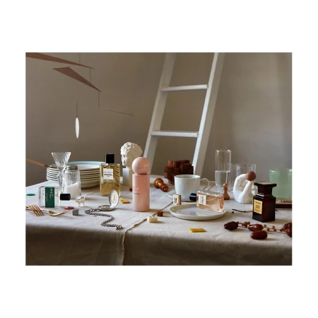 Still life shot of assorted perfume bottles, a salt shaker, and chess pieces arranged on a linen tablecloth with soft, diffused lighting.