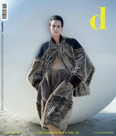 Model wearing a textured fur coat and matching trousers posing against a large white sphere on a beach by Liv Liberg