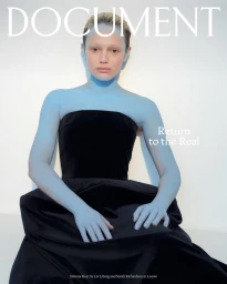 Model with blue body paint wearing a black strapless velvet gown against a white background for a magazine editorial by Liv Liberg