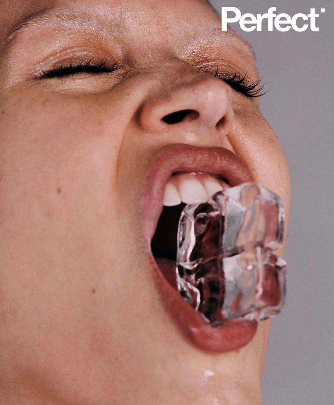 Close-up portrait of a woman with ice cubes in her mouth against a grey background, featuring the "Perfect" logo in the upper right.