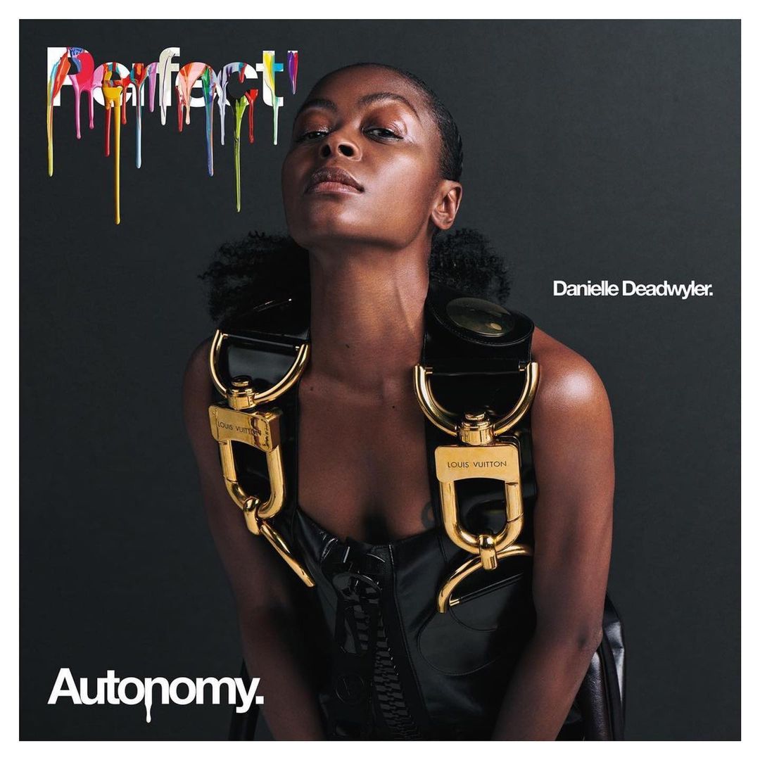 Portrait of Danielle Deadwyler against dark background. She's wearing a black patent leather corset with gold Louis Vuitton hardware.