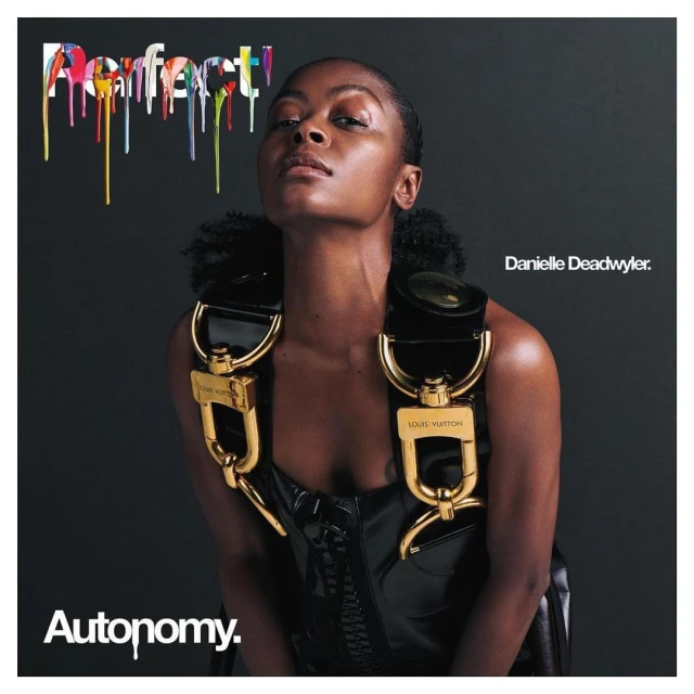 Portrait of Danielle Deadwyler against dark background. She's wearing a black patent leather corset with gold Louis Vuitton hardware.