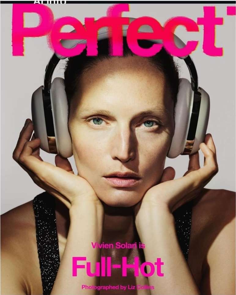 Magazine cover featuring a fair-skinned woman with headphones, gazing directly at the camera, set against a light gray background.