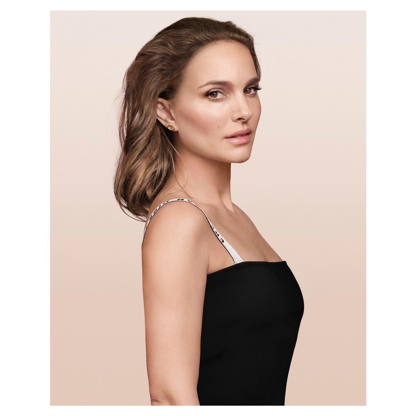Portrait of a woman with brown hair wearing a black top, captured in a studio setting with soft, diffused lighting.