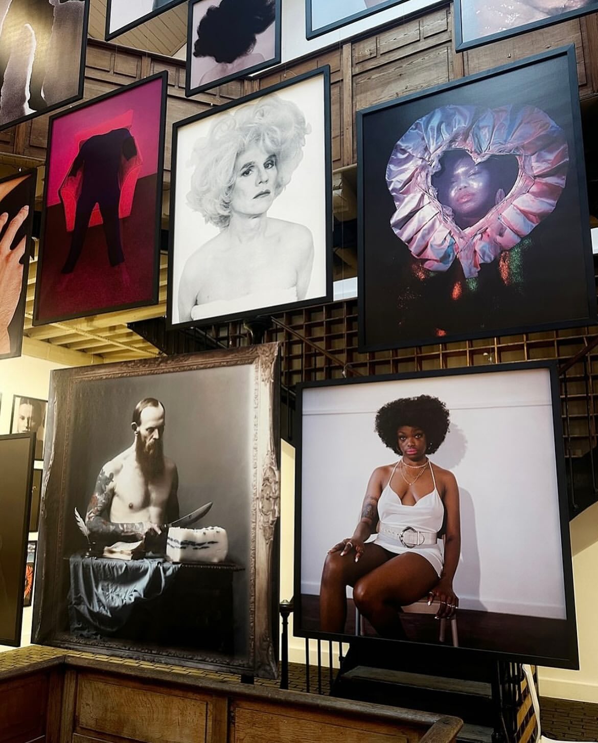 Artwork display features framed portrait photographs of diverse subjects in a gallery setting with warm lighting, capturing artistic expressions.