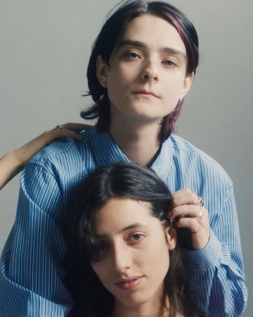 Portrait of two people in blue striped shirts photographed by Lola and Pani against a plain grey studio background.