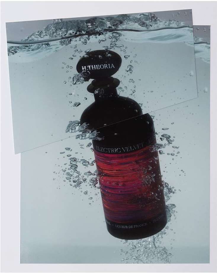 Stylized product shot of a dark bottle with Electric Velvet label submerged in water with bubbles, set against a white background.