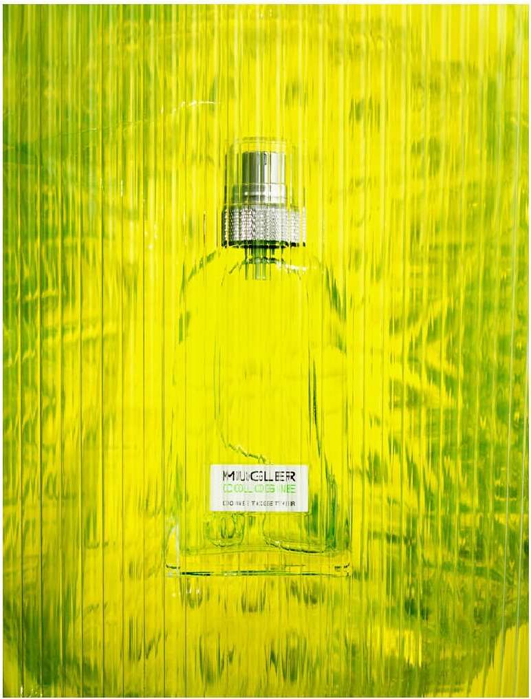 Close-up studio shot of a clear glass perfume bottle filled with green liquid, featuring a textured yellow-green background.