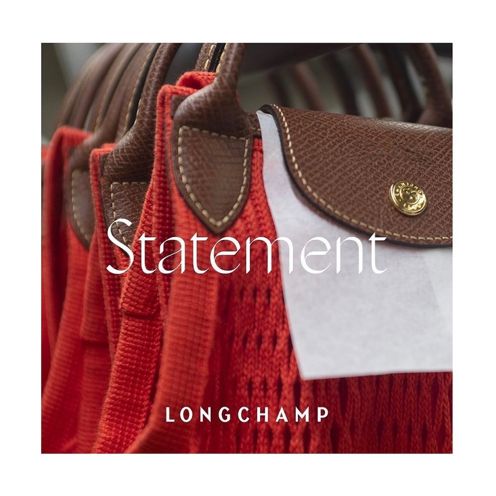 Close-up of Longchamp bags in red with brown leather handles and flaps, arranged in a row, showcasing the brand's design.