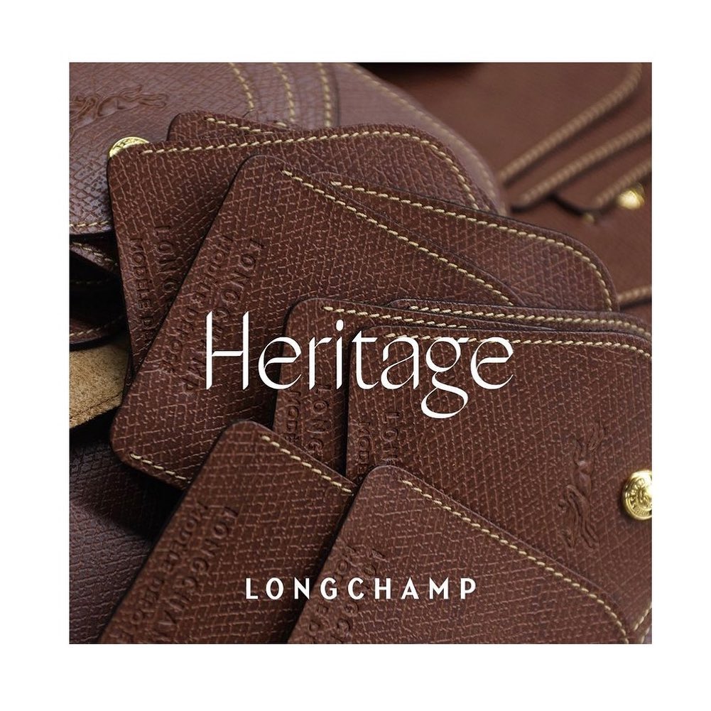 Close-up on the Longchamp Heritage leather goods collection featuring a brown leather flap bag with a gold snap closure and visible stitching.