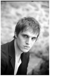 Portrait of a young man wearing a dark jacket and white t-shirt, photographed by Lou Levy in Paris.