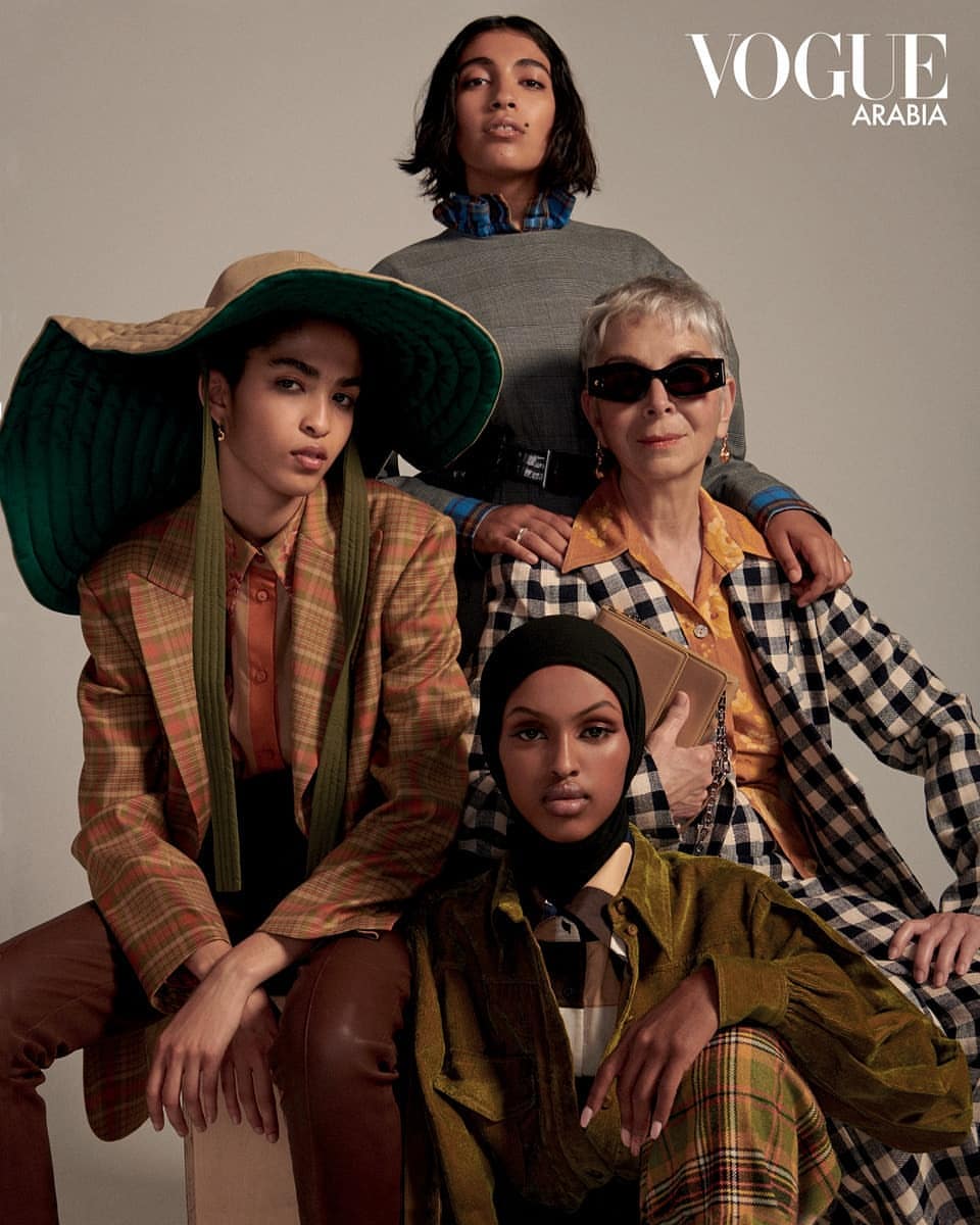 Four diverse women pose together in a Vogue Arabia fashion editorial. They wear stylish patterned outfits with a solid grey backdrop.