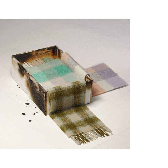 Wool scarves in a rustic box. Colorful plaid scarves made of wool are arranged in a charred, wooden box for product photography.