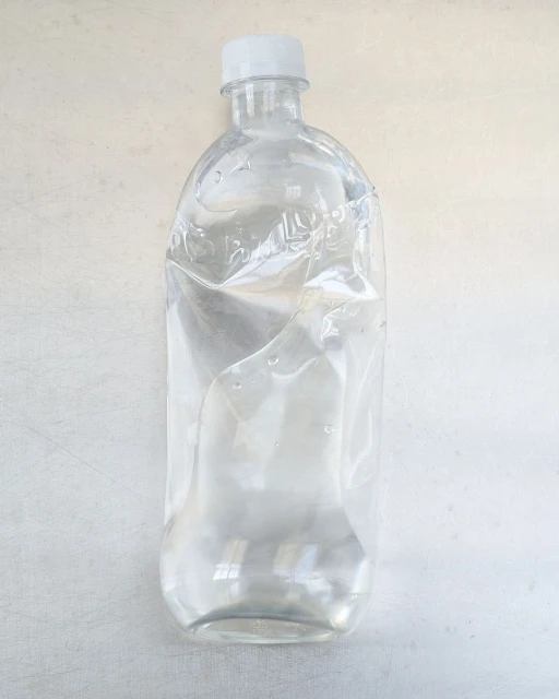 Clear, slightly crumpled water bottle on a white surface, with a white cap. The bottle is partially filled with water, minimal aesthetic.