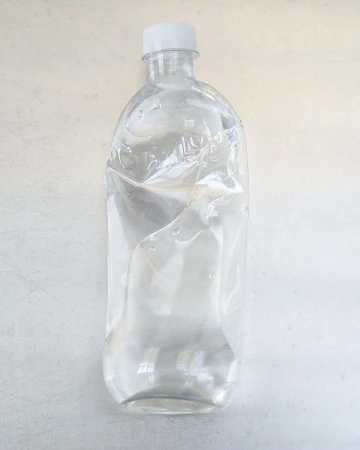 Clear, slightly crumpled water bottle on a white surface, with a white cap. The bottle is partially filled with water, minimal aesthetic.