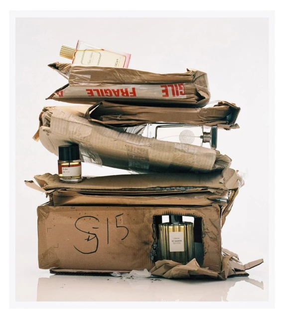 Stack of packaged perfumes in cardboard boxes, showcasing a variety of fragrances and bottle designs against a clean white background.