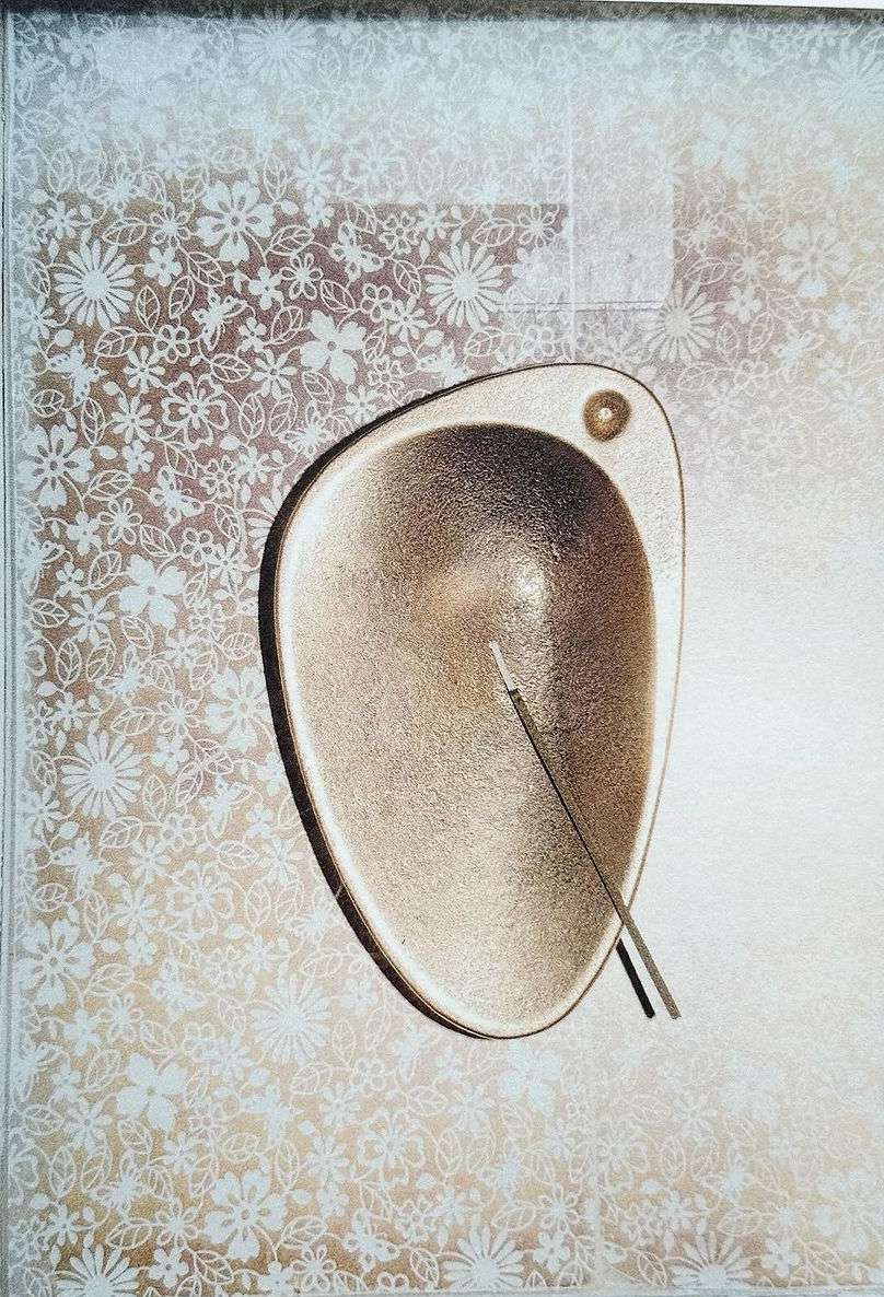 Abstract surreal art featuring a gold metallic bowl on a silver background with white floral patterns and two thin sticks.