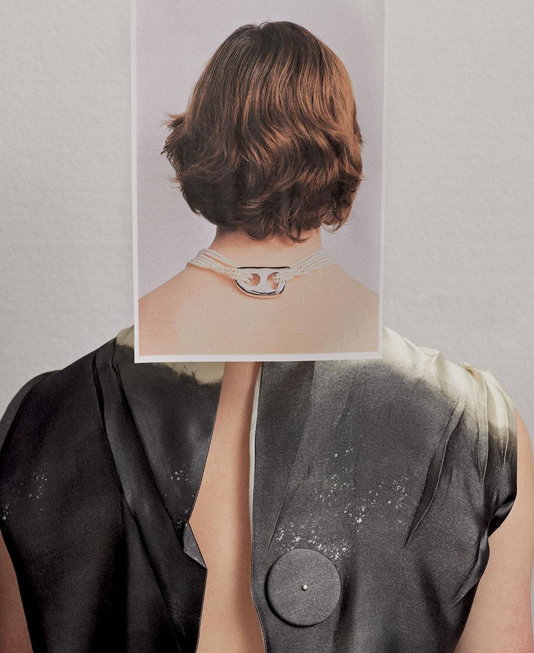 Back view of a person with a gray-scale shirt and a photograph placed over their neck showing the back of another person's head and a necklace.