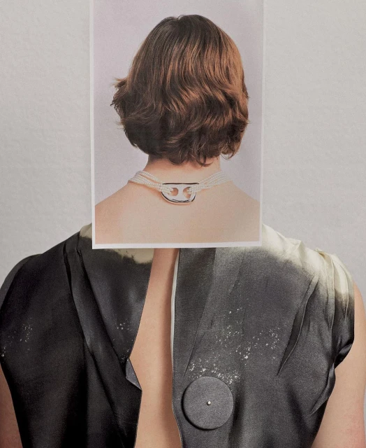 Back view of a person with a gray-scale shirt and a photograph placed over their neck showing the back of another person's head and a necklace.