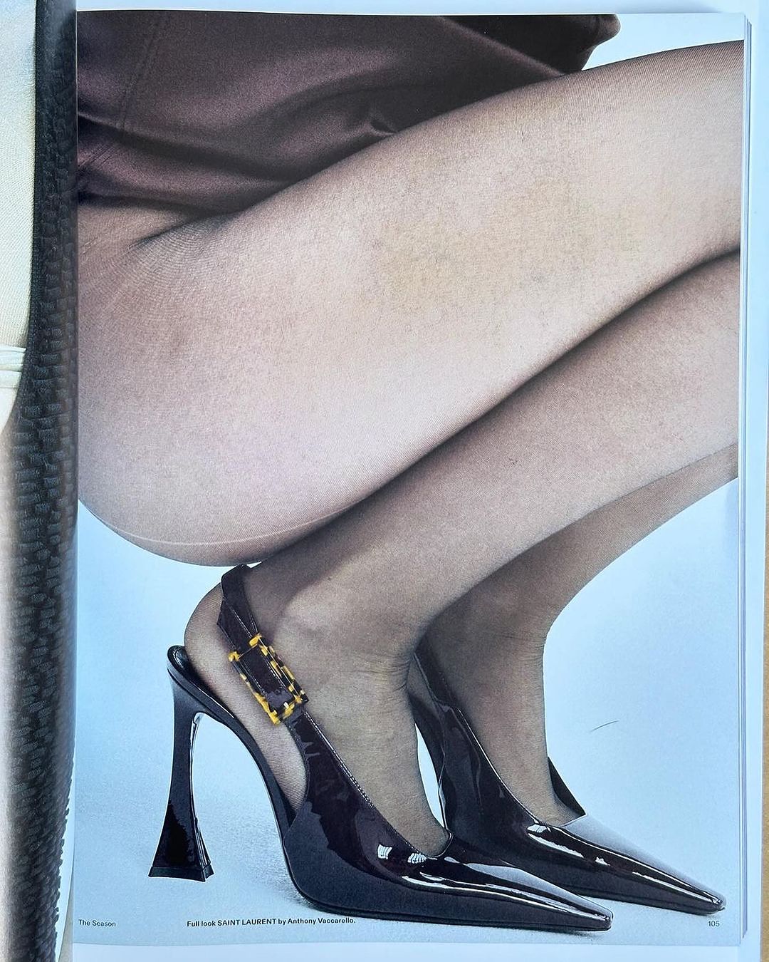 Fashionable pose of woman showcasing black high-heeled slingbacks with tortoiseshell buckle, reflecting a high-fashion aesthetic.