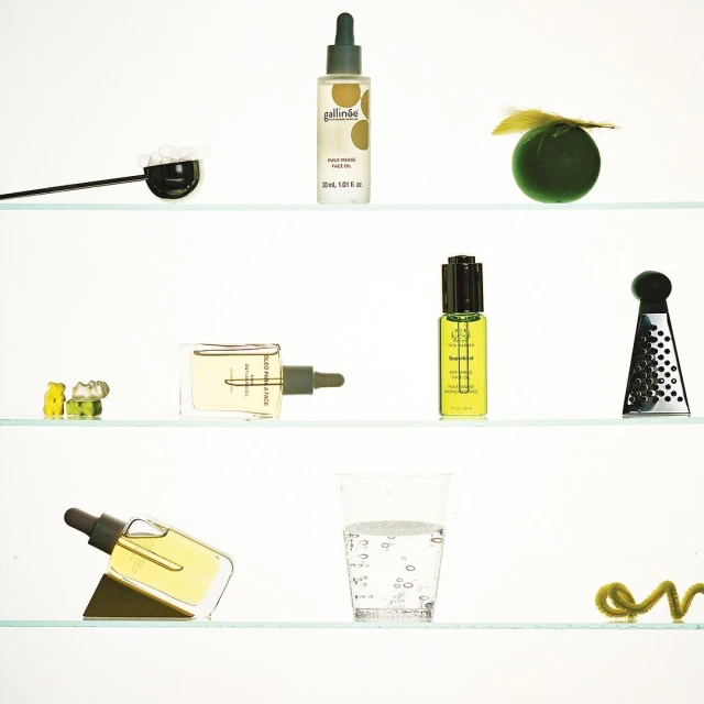 Botanical beauty product arrangement on shelves featuring skincare oil bottles, glass of water, and abstract decorative elements.
