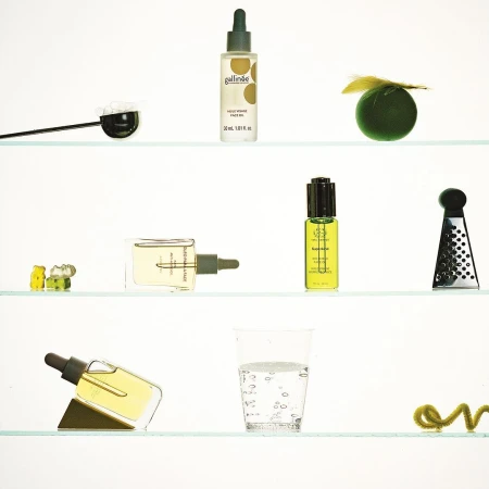 Botanical beauty product arrangement on shelves featuring skincare oil bottles, glass of water, and abstract decorative elements.