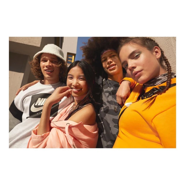 Group of four diverse young adults wearing sports apparel in urban setting, smiling and posing for a fashion forward lifestyle shot.