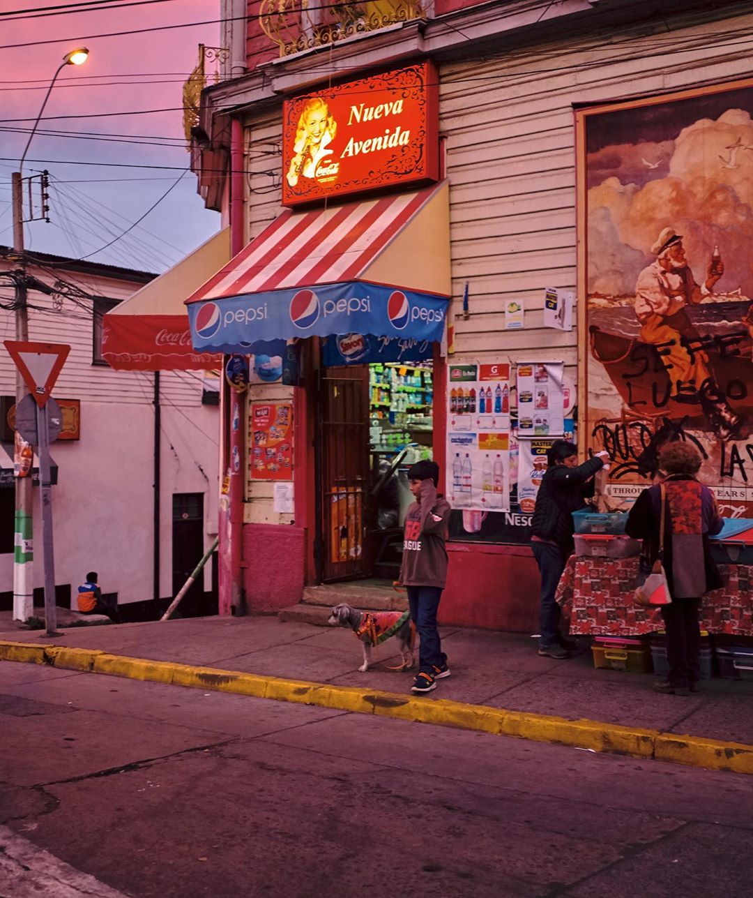 A daytime street view showcases a child with a dog, several adults, commercial awnings, and a building mural under a pink-tinged sky.