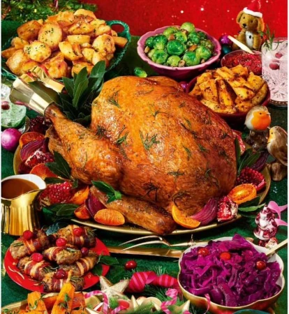 Overhead shot of a festive Thanksgiving or Christmas dinner featuring a whole roasted turkey with potatoes and vegetables on a table.
