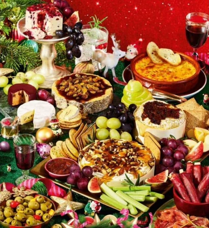 Festive holiday appetizer spread with an assortment of cheeses, olives, grapes, crackers, bread, salami, and a glass of red wine.