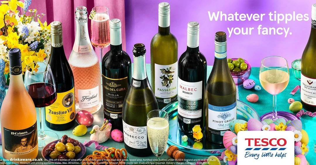 Assortment of wine bottles and glasses alongside Easter decorations and snacks, set against a purple backdrop in a promotional display.