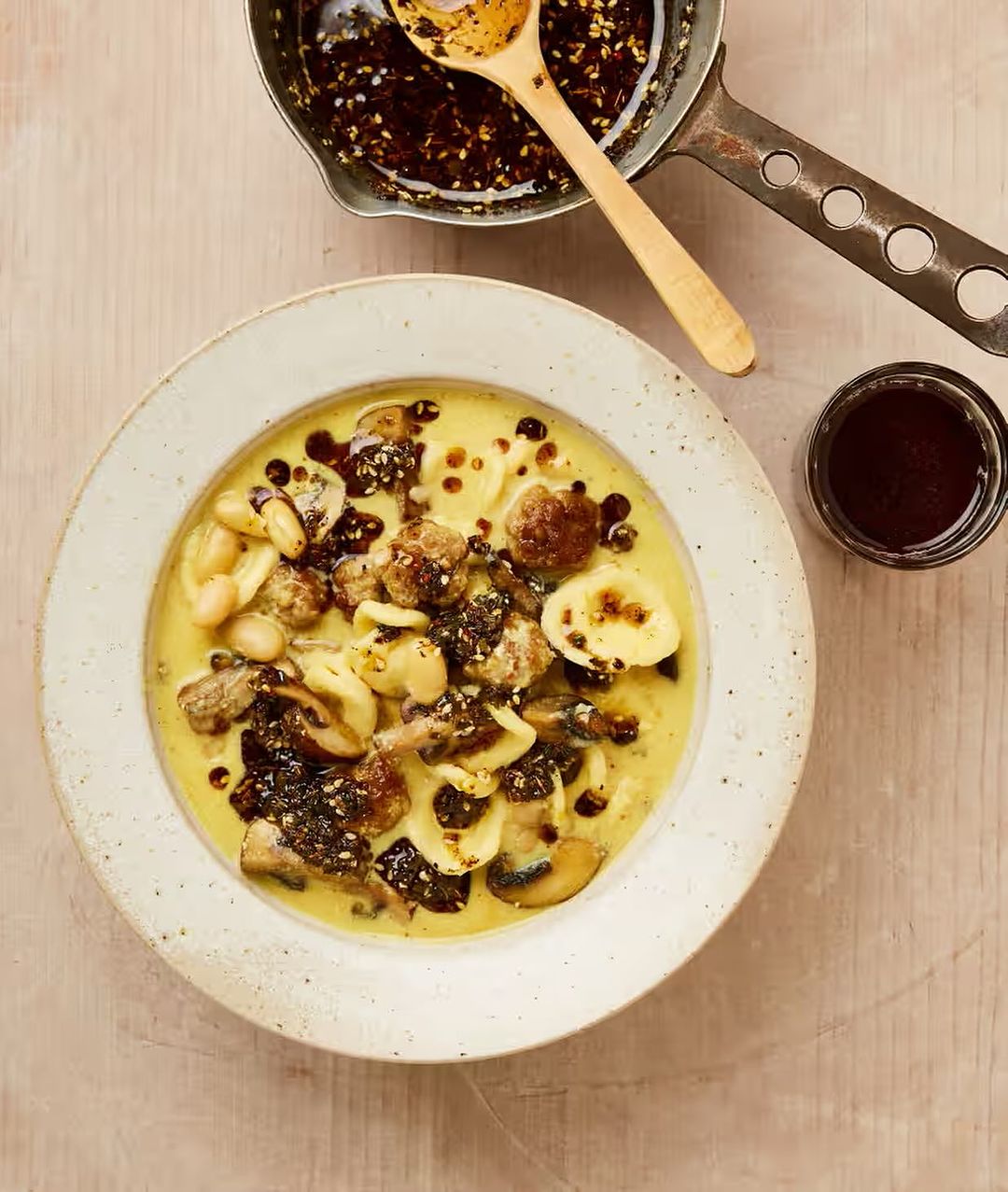 Overhead view of orecchiette pasta with mushrooms and white beans in creamy yellow sauce, drizzled with dark balsamic glaze.